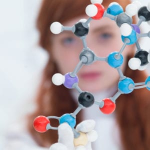 young red-headed woman holding up a molecule model